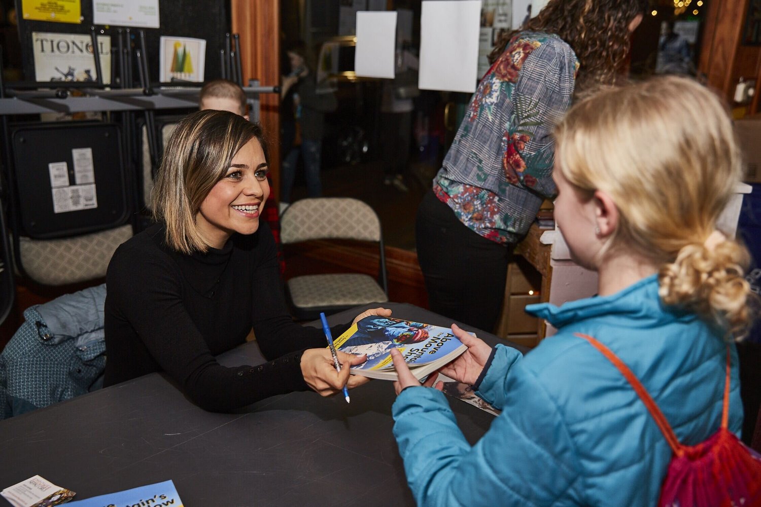 Dr. Sara Safari signing a copy of her book for a girl at a book signing