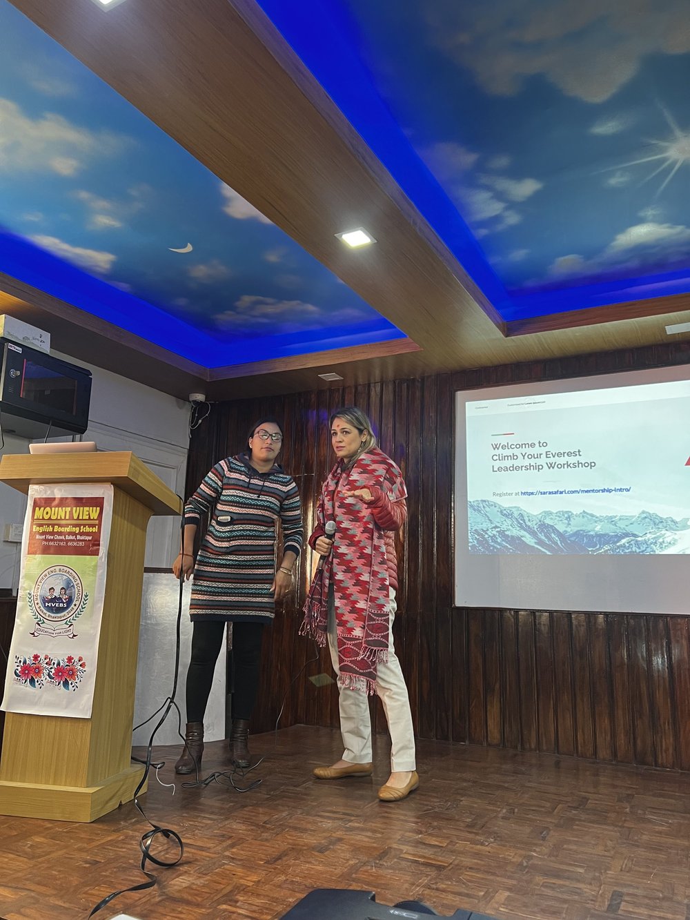 Two facilitators opening a Climb Your Everest leadership workshop on stage