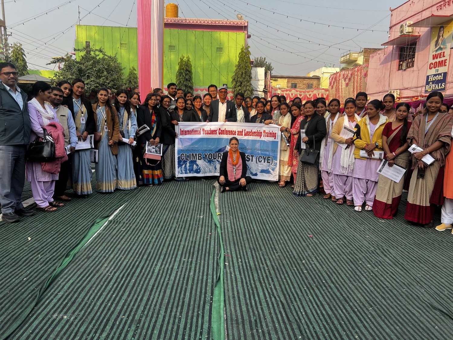 A large group of teachers outside with the Climb Your Everest conference banner